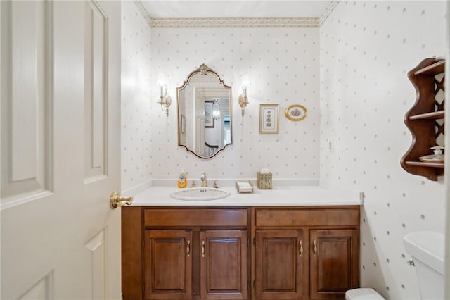 half bath with vanity, toilet, and wallpapered walls