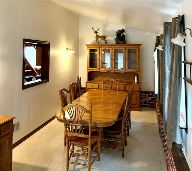 carpeted dining space with lofted ceiling