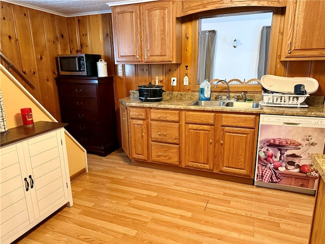 kitchen with appliances with stainless steel finishes, light wood-type flooring, wood walls, crown molding, and sink