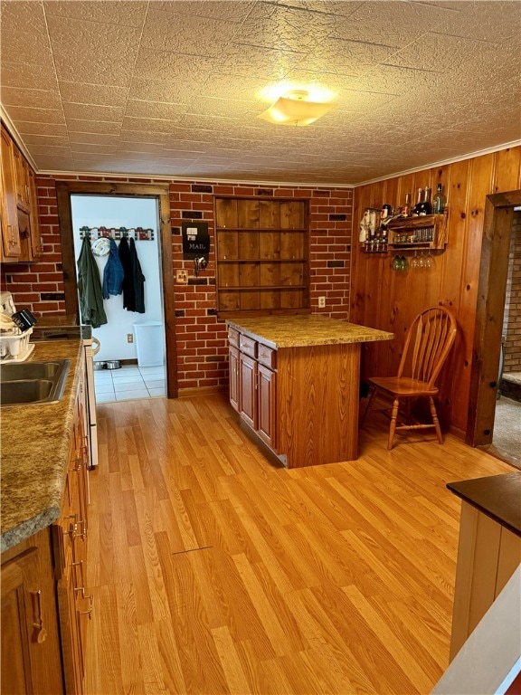 kitchen with brick wall, wooden walls, and light hardwood / wood-style flooring