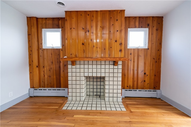 unfurnished living room featuring a baseboard radiator, hardwood / wood-style flooring, and plenty of natural light