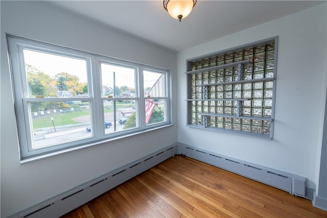 unfurnished room with wood-type flooring and a baseboard heating unit