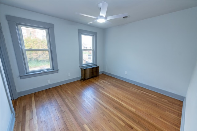 unfurnished room with light hardwood / wood-style floors, radiator, and ceiling fan