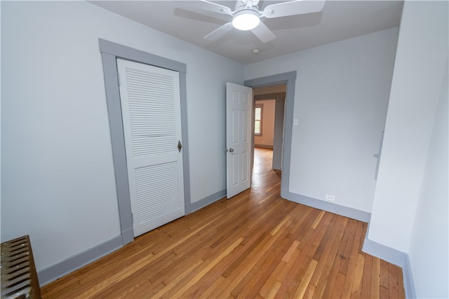 unfurnished bedroom featuring a closet, radiator, light hardwood / wood-style floors, and ceiling fan