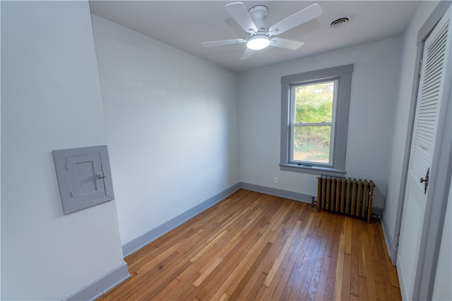 unfurnished bedroom featuring radiator, ceiling fan, a closet, and light hardwood / wood-style flooring