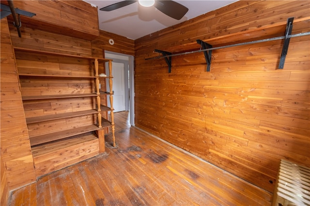 unfurnished room featuring hardwood / wood-style flooring, wooden walls, and ceiling fan