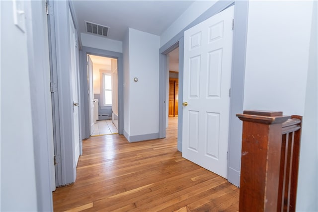 corridor featuring baseboard heating and light wood-type flooring