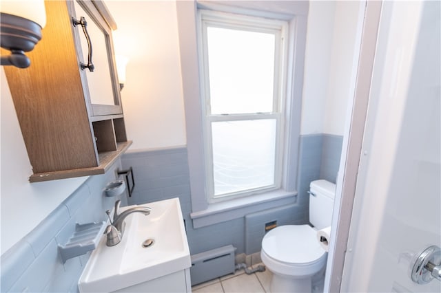 bathroom with tile patterned floors, toilet, a baseboard radiator, vanity, and tile walls