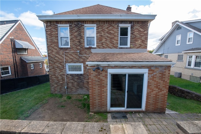 rear view of house featuring central AC unit and a lawn