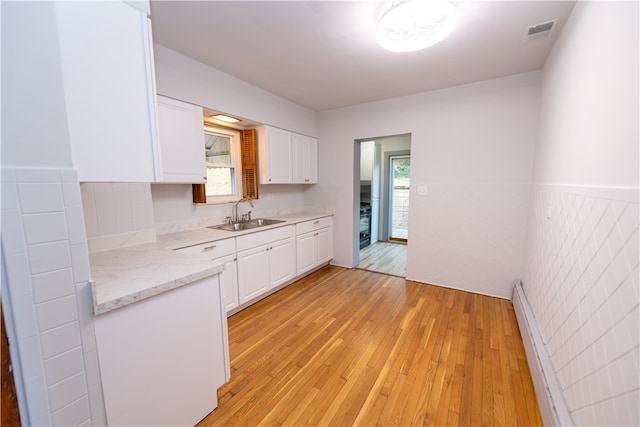 kitchen featuring sink, light hardwood / wood-style flooring, white cabinetry, and a healthy amount of sunlight