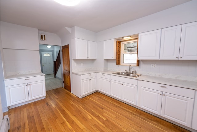 kitchen with light hardwood / wood-style floors, white cabinets, sink, and a baseboard radiator