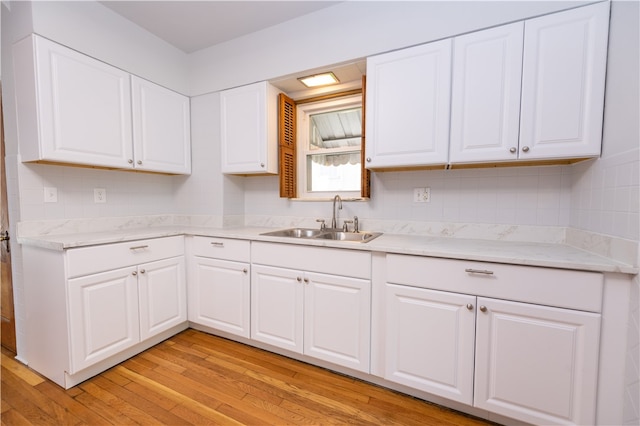 kitchen with white cabinetry, sink, and light wood-type flooring