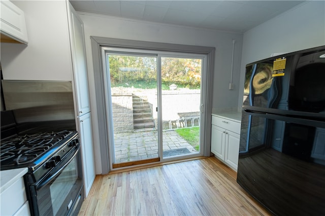 kitchen featuring ornamental molding, black appliances, white cabinets, and light hardwood / wood-style floors