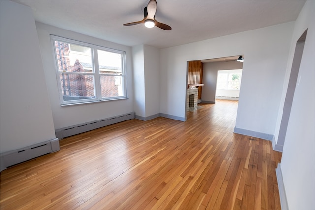 spare room with a baseboard heating unit, light wood-type flooring, and ceiling fan