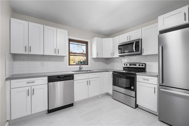 kitchen with white cabinets, backsplash, appliances with stainless steel finishes, light tile patterned flooring, and sink