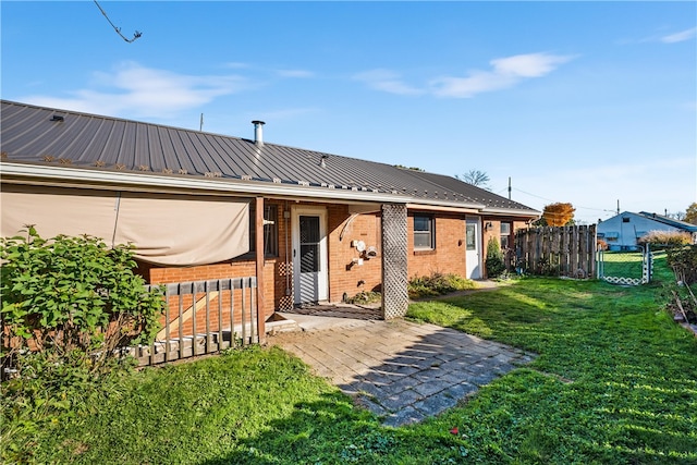 back of house with a patio and a lawn