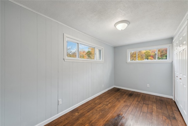 unfurnished bedroom featuring a closet, a textured ceiling, and dark hardwood / wood-style flooring