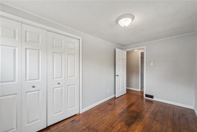 unfurnished bedroom featuring a textured ceiling, dark hardwood / wood-style floors, and a closet