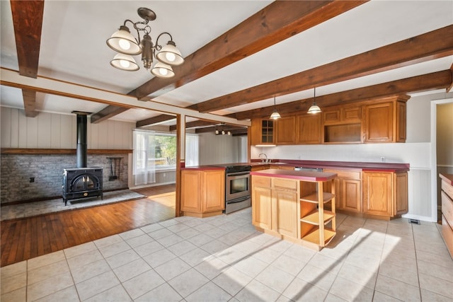 kitchen featuring beamed ceiling, light hardwood / wood-style flooring, a wood stove, electric range, and a notable chandelier