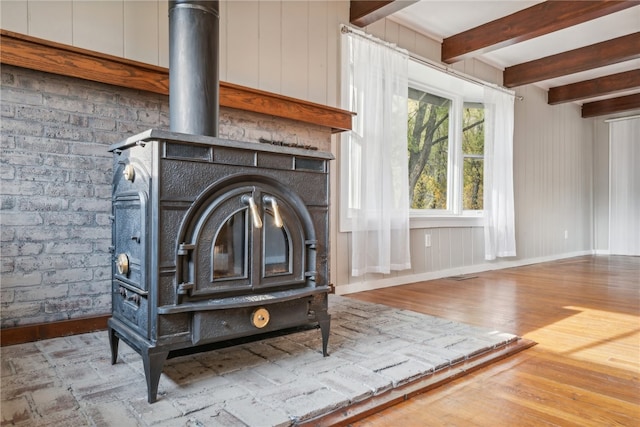 interior details featuring beamed ceiling, hardwood / wood-style floors, and a wood stove