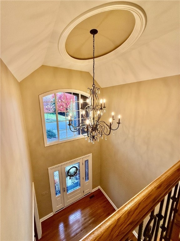 foyer featuring dark hardwood / wood-style floors, a chandelier, a raised ceiling, and vaulted ceiling