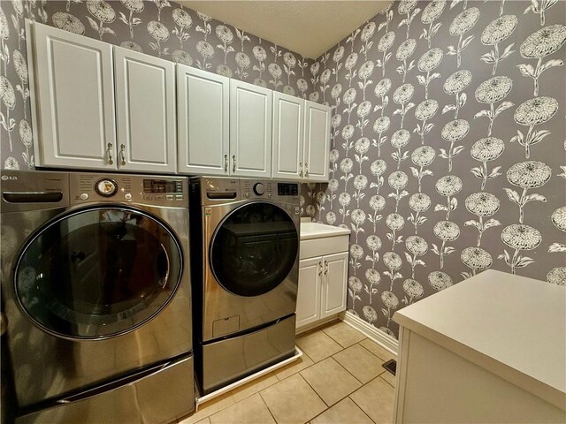 laundry area featuring light tile patterned floors, separate washer and dryer, and cabinets