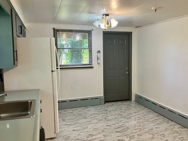 interior space with white fridge, a baseboard heating unit, and sink