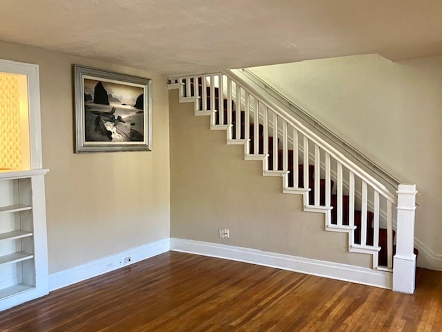 stairway with hardwood / wood-style flooring and built in shelves