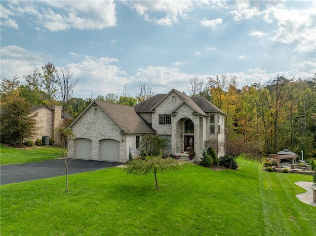 french country style house featuring a garage and a front lawn