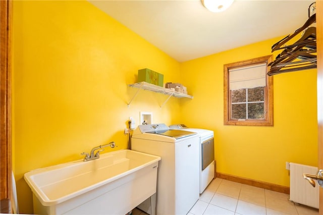 clothes washing area featuring light tile patterned floors, radiator heating unit, washer and clothes dryer, and sink