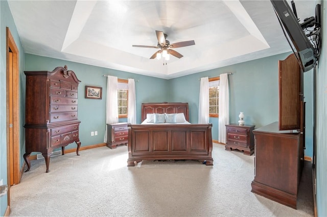 carpeted bedroom with ceiling fan and a tray ceiling