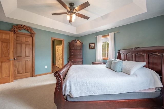 carpeted bedroom featuring ceiling fan and a tray ceiling