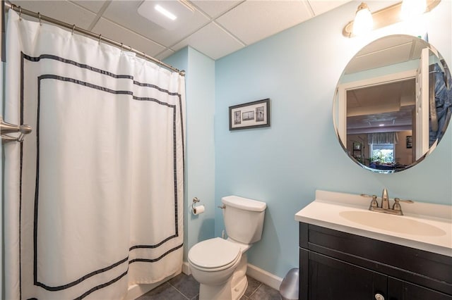 bathroom with toilet, a drop ceiling, vanity, and tile patterned flooring