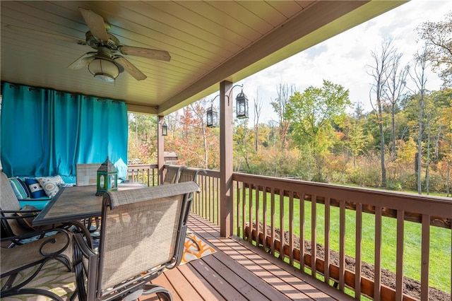 wooden terrace featuring ceiling fan and a yard