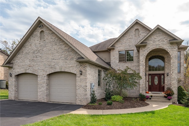 french country inspired facade featuring a garage and central air condition unit