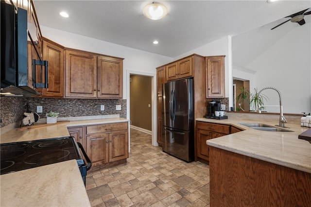 kitchen featuring sink, kitchen peninsula, stainless steel fridge, lofted ceiling, and decorative backsplash