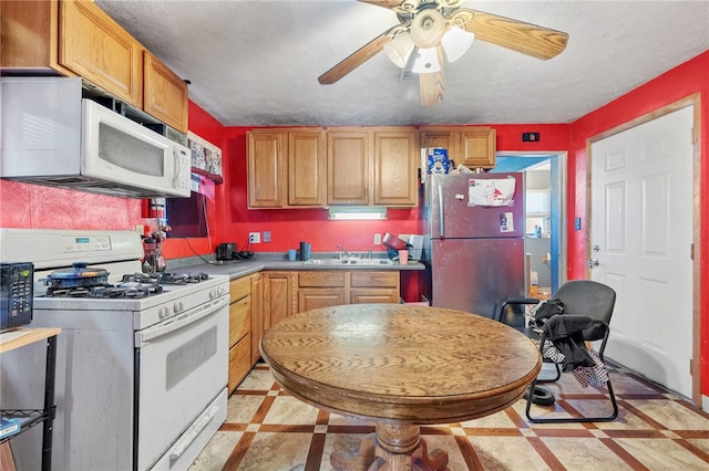 kitchen with a textured ceiling, ceiling fan, sink, and white appliances