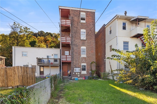 back of house featuring a yard and a balcony