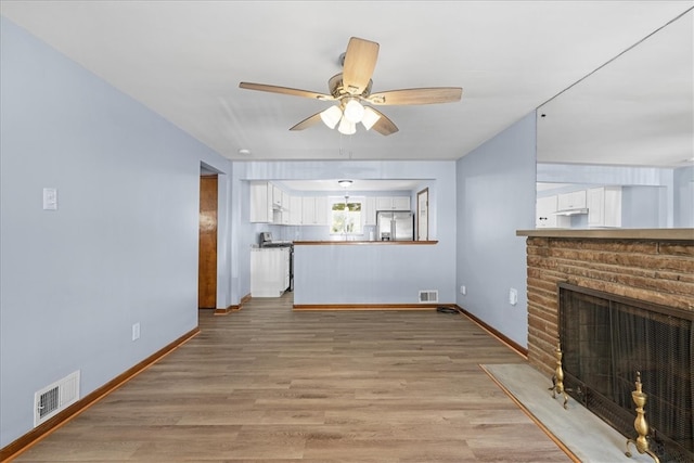 unfurnished living room with a fireplace, hardwood / wood-style flooring, and ceiling fan