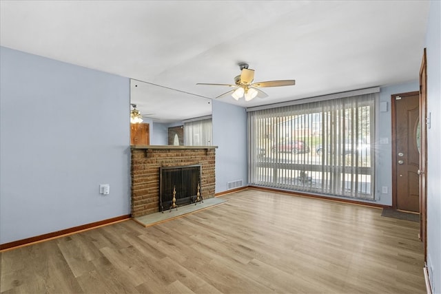 unfurnished living room with hardwood / wood-style floors, a brick fireplace, and ceiling fan