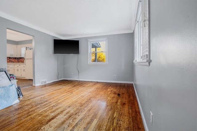 interior space with white fridge, ensuite bath, and hardwood / wood-style flooring