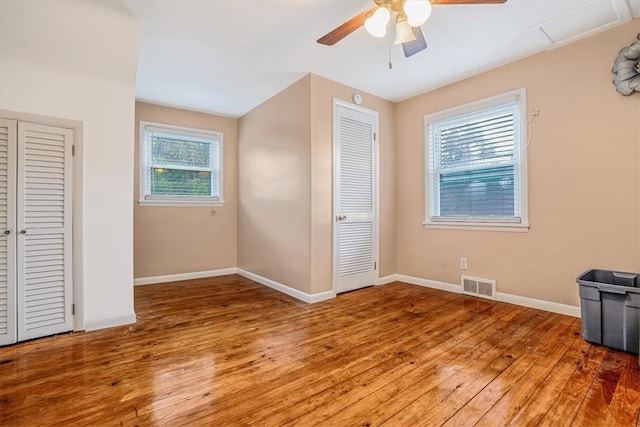 unfurnished bedroom with multiple windows, ceiling fan, and hardwood / wood-style floors