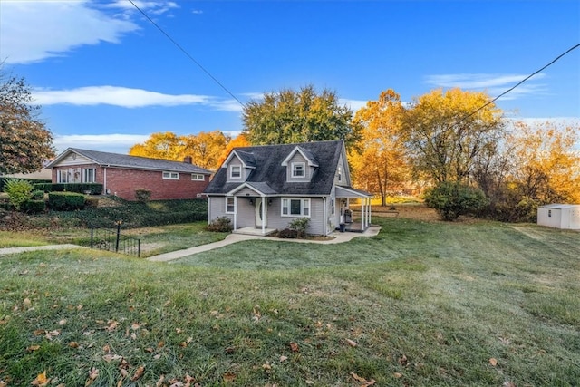 cape cod home featuring a shed and a front lawn