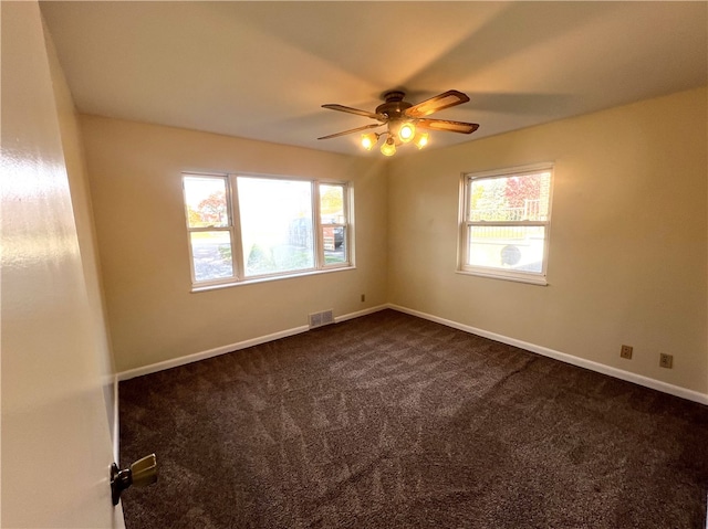 unfurnished room with ceiling fan and dark carpet