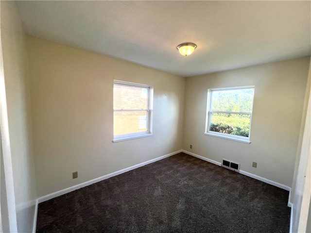 empty room featuring a healthy amount of sunlight and dark carpet