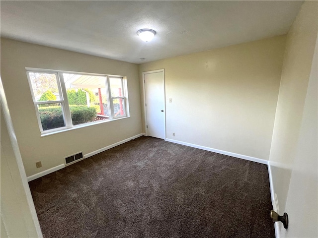 spare room featuring dark colored carpet