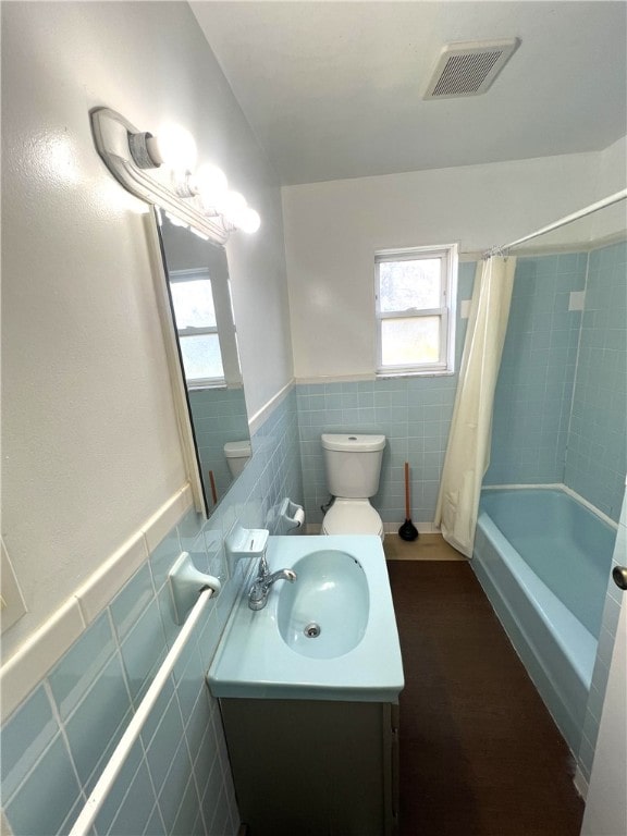 full bathroom featuring toilet, vanity, shower / bath combination with curtain, and tile walls