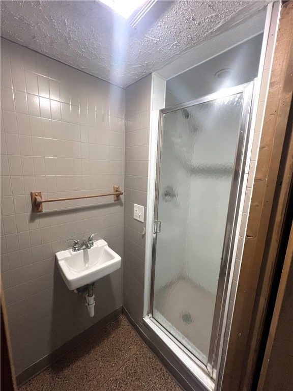 bathroom with a textured ceiling, walk in shower, and sink