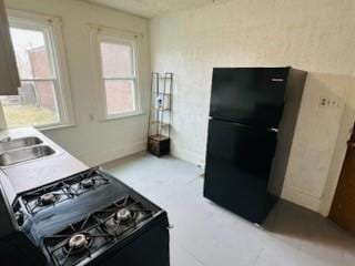 kitchen featuring light countertops, plenty of natural light, a sink, and black appliances