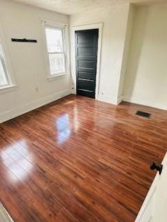 spare room featuring baseboards, visible vents, and wood finished floors